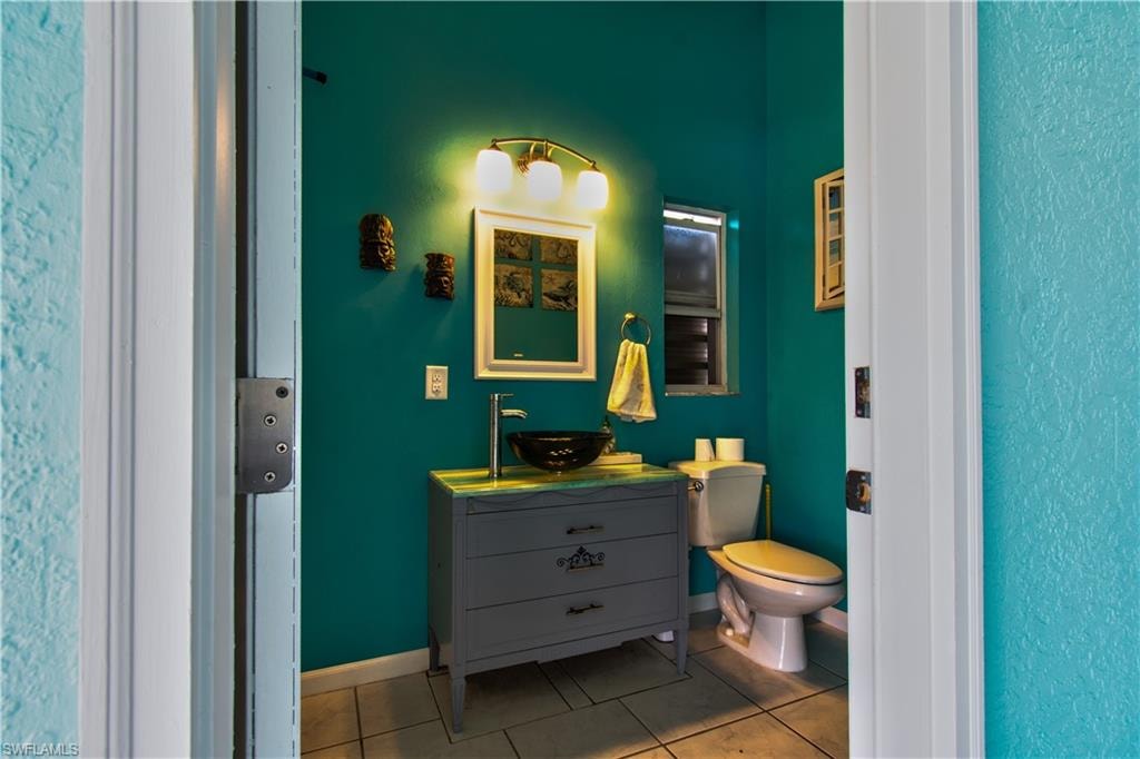 Bathroom with vanity, a textured wall, and tile patterned flooring