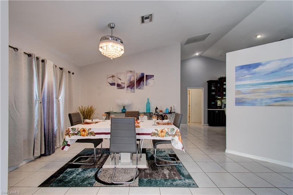 Dining area featuring vaulted ceiling, light tile patterned flooring, recessed lighting, and a chandelier