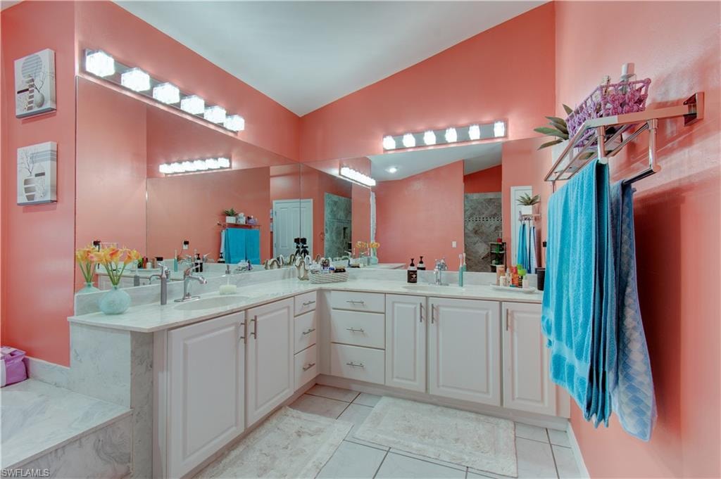 Full bathroom with double vanity, vaulted ceiling, a tile shower, light tile patterned floors, and a bath