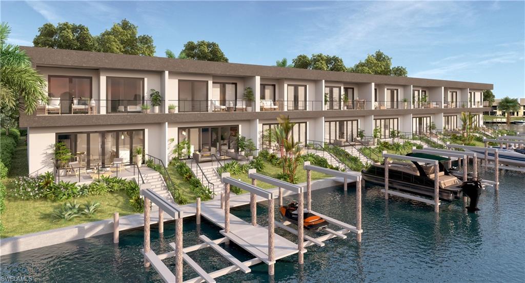 Rear view of property with boat lift, stucco siding, a water view, and a balcony