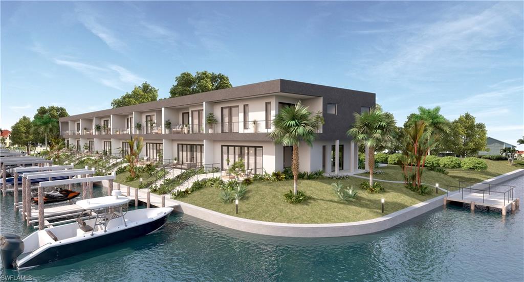 Rear view of house with a yard, stucco siding, a water view, and boat lift