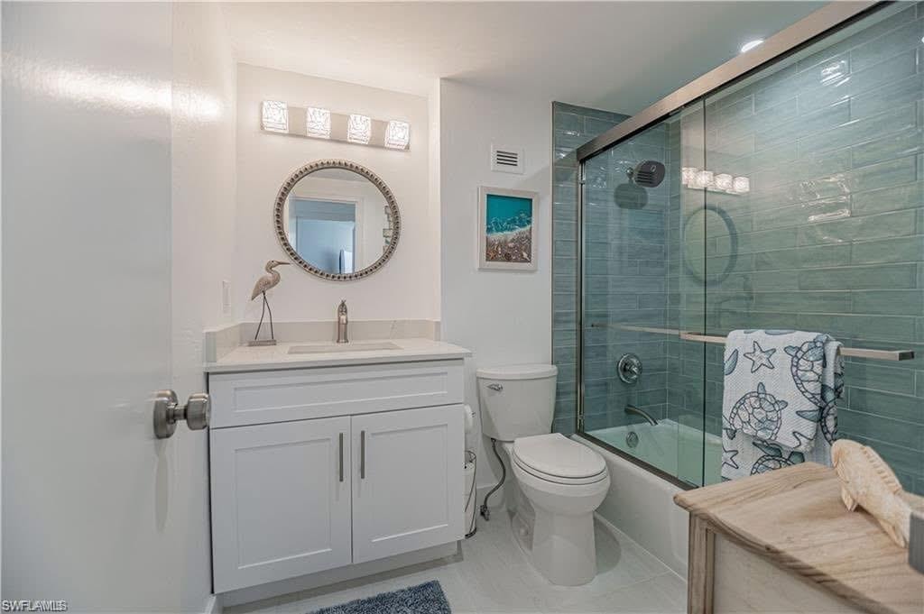 Full guest bathroom featuring vanity, bath / shower combo with glass door, and light tiled flooring