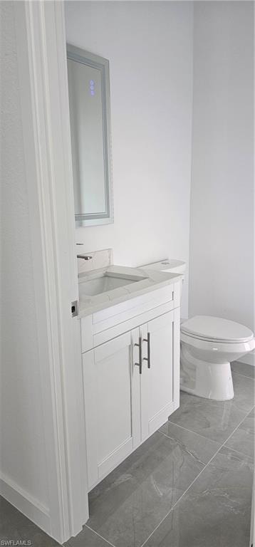 Half bathroom featuring vanity and dark marble finish floors