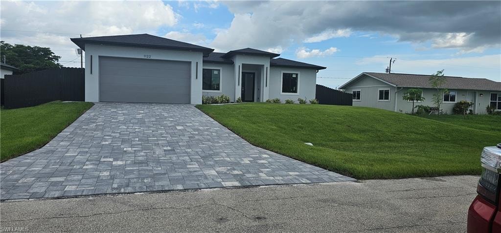 View of front of house with decorative driveway, stucco siding, and an attached garage