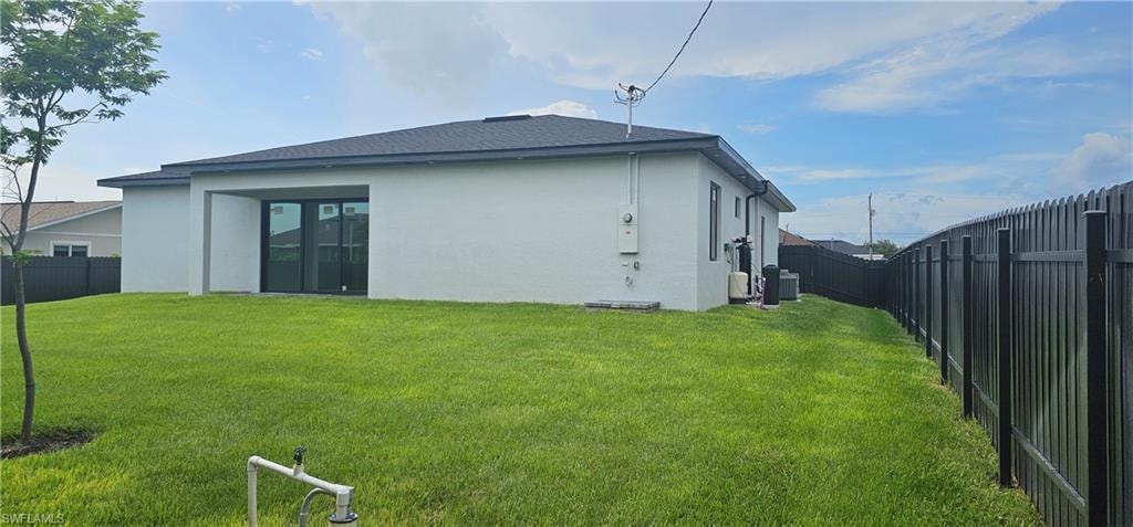 Back of property featuring a fenced backyard, stucco siding, and a shingled roof