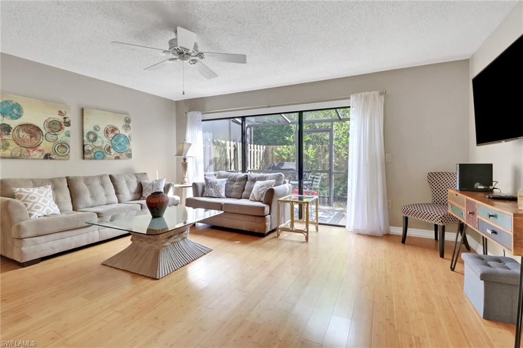 Living room featuring light wood finished floors, a textured ceiling, and a ceiling fan