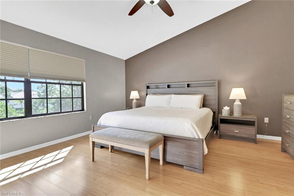 Bedroom with vaulted ceiling, light wood-style floors, and ceiling fan