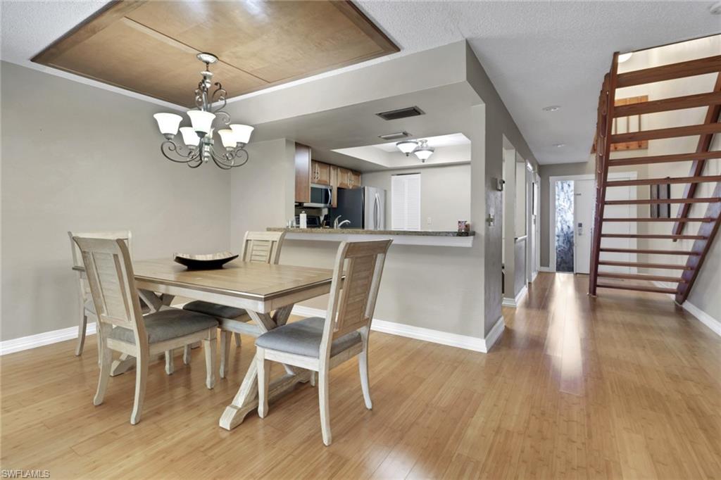 Dining room featuring light wood-style flooring, a chandelier, and stairs