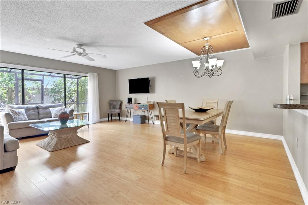 Dining space with light wood-type flooring, a chandelier, ceiling fan, and a textured ceiling