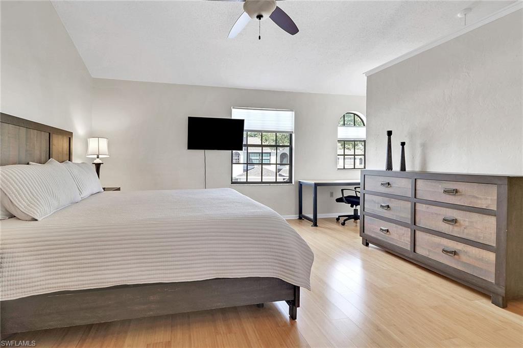 Bedroom featuring light wood-type flooring, ceiling fan, an office area, and a textured ceiling