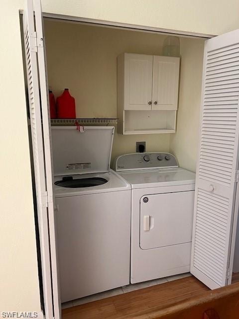 Washroom featuring cabinet space, separate washer and dryer, and light wood-style floors