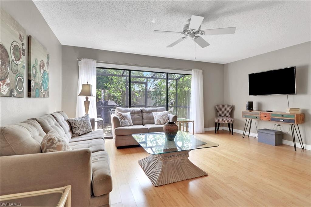 Living room featuring light wood-style floors, a textured ceiling, and a ceiling fan
