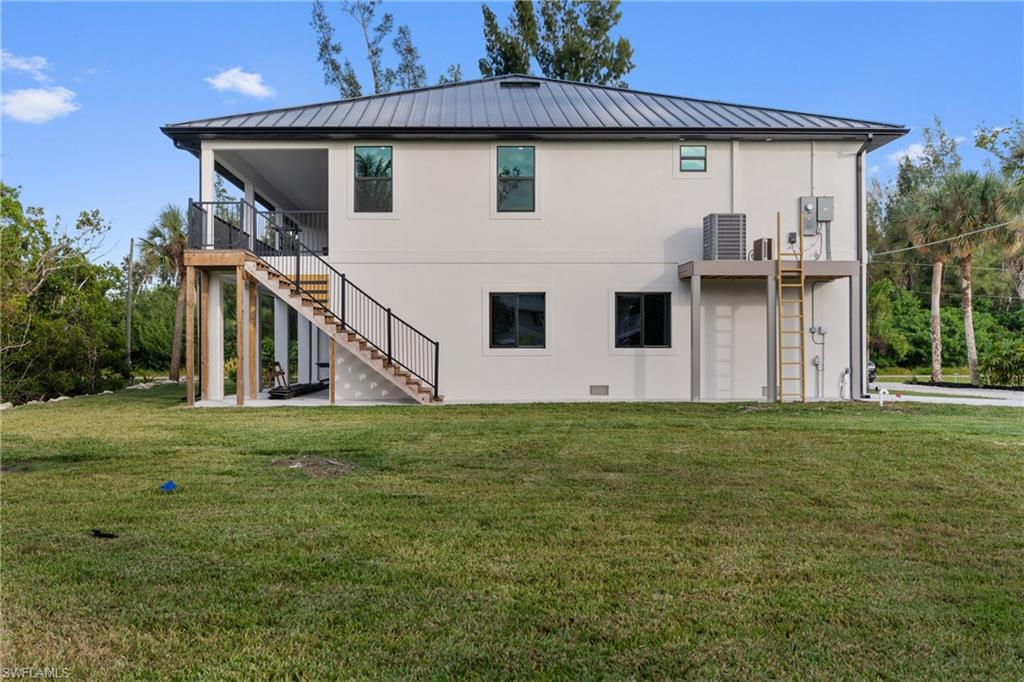 Back of property featuring a yard, stairway, a patio, and a standing seam roof