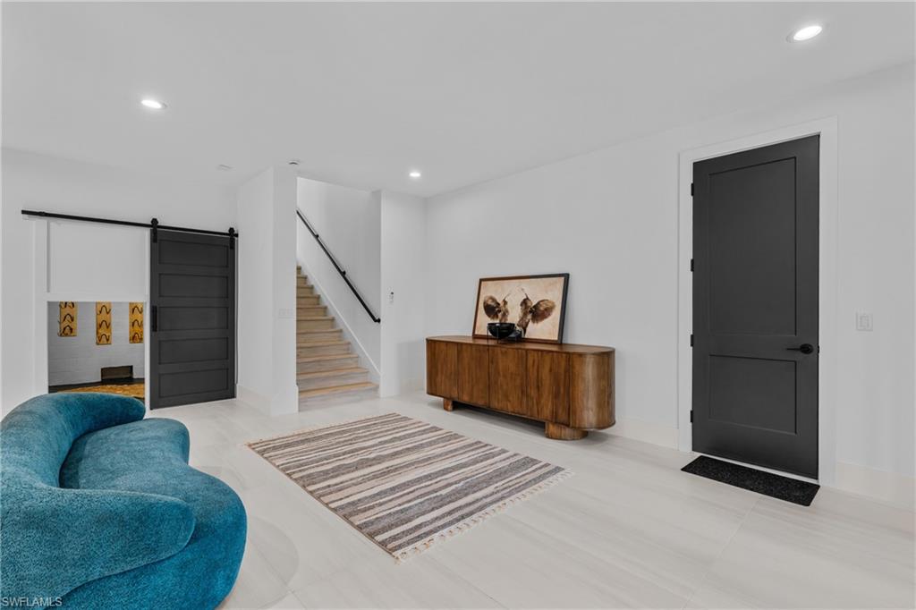 Living area with a barn door, recessed lighting, and stairs