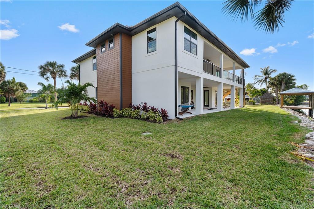 Back of house with a patio area, a lawn, stucco siding, and a balcony