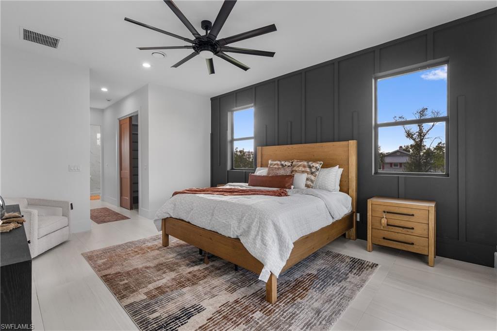 Bedroom featuring a decorative wall, recessed lighting, a ceiling fan, and ensuite bath
