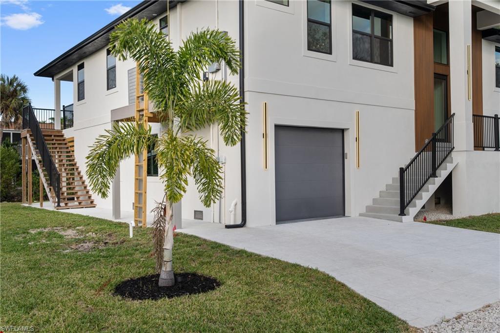 View of front of property featuring stairway, a garage, stucco siding, and a front yard