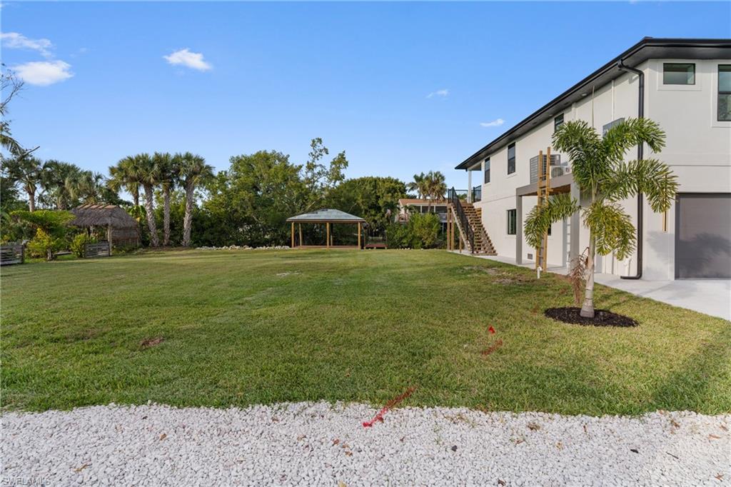 View of grassy yard with stairs and a gazebo