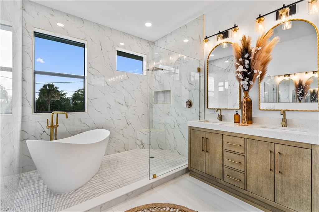 Full bathroom with double vanity, a marble finish shower, recessed lighting, and a soaking tub