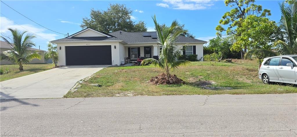 View of front facade with stucco siding, a front yard, concrete driveway, roof mounted solar panels, and an attached garage