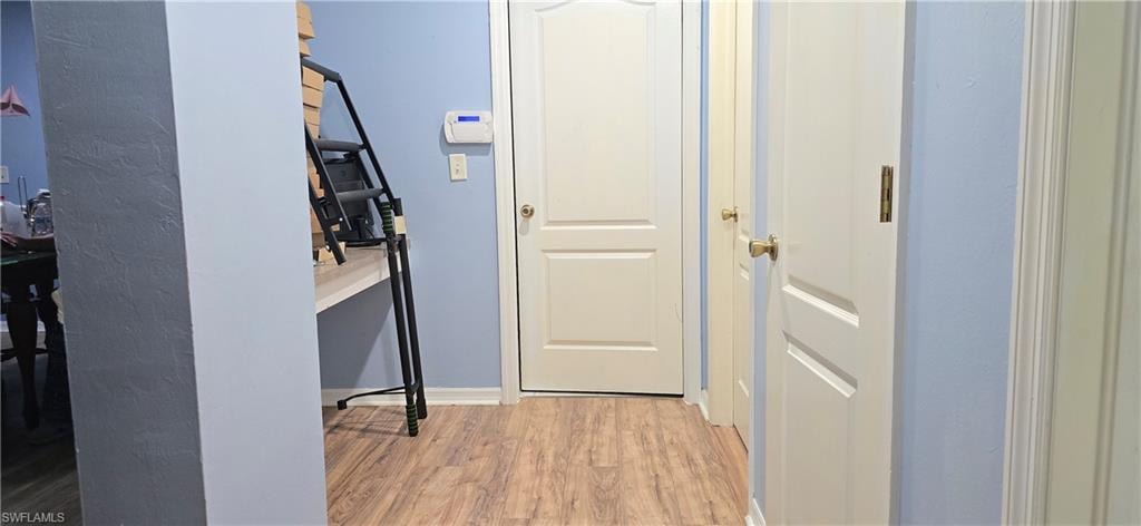 Hallway featuring light wood-type flooring and baseboards