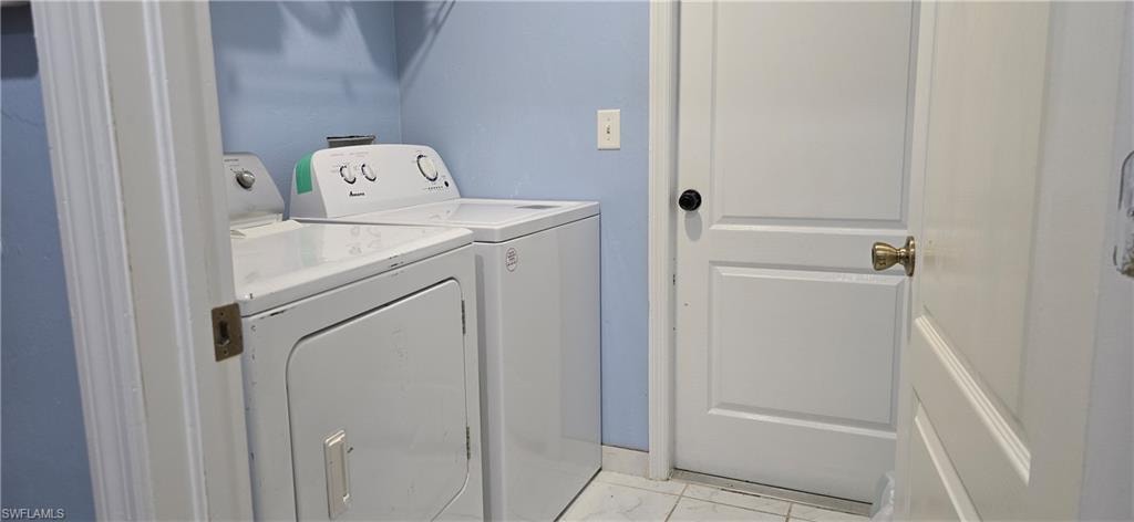 Washroom featuring independent washer and dryer and light marble finish floors