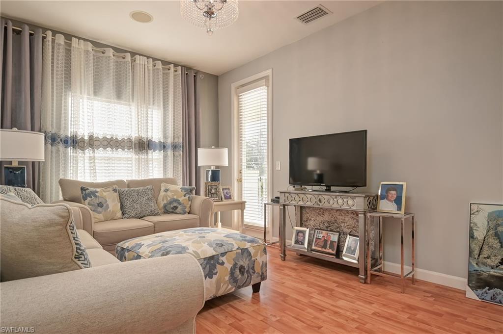 Living area featuring light wood-style floors, plenty of natural light, and a chandelier