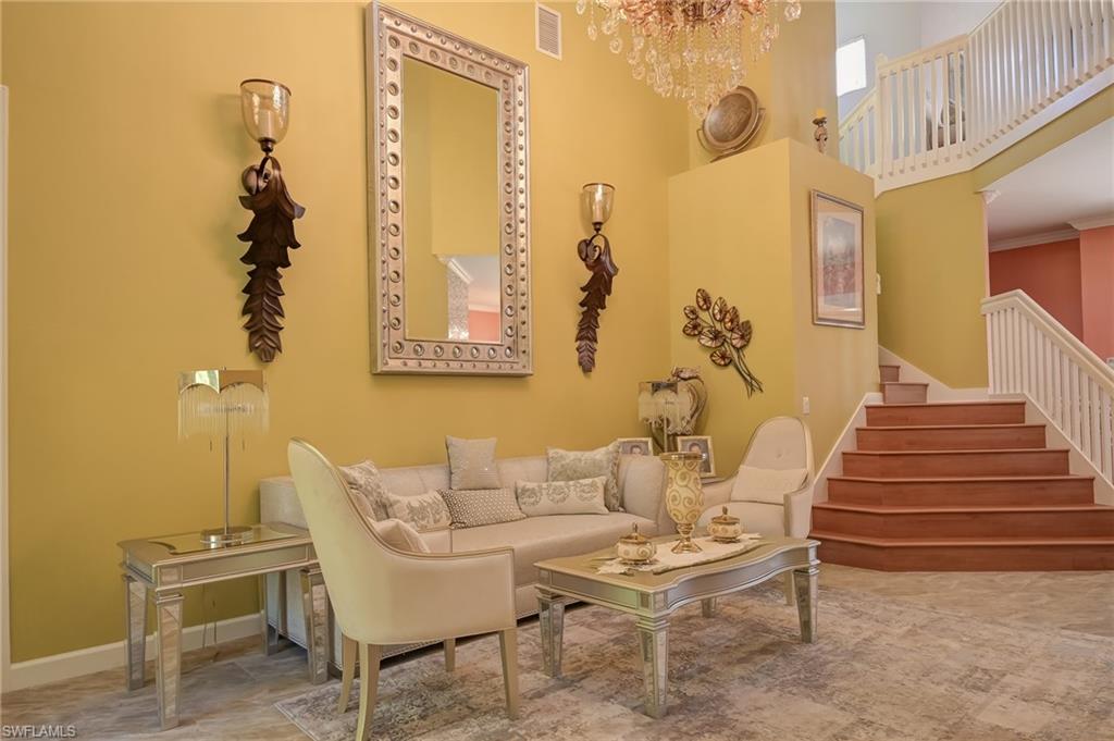 Sitting room with a towering ceiling, stairs, and a chandelier