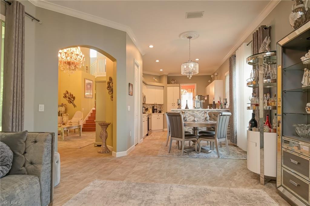 Dining area with a chandelier, crown molding, arched walkways, stairway, and recessed lighting