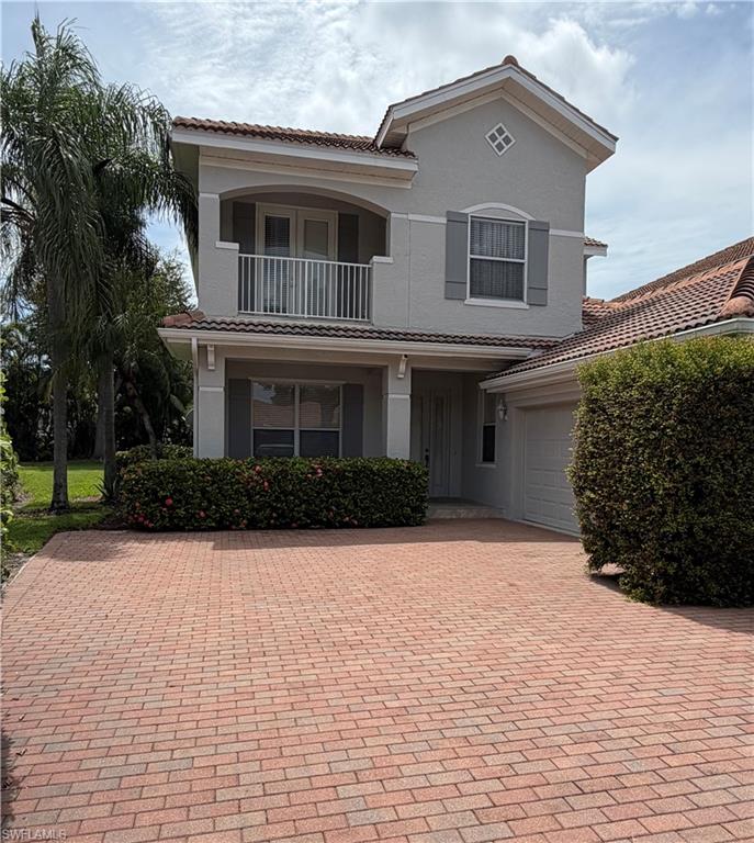 Two-story stucco exterior featuring a Mediterranean tile roof, a second-story balcony with white railing, and decorative window shutters