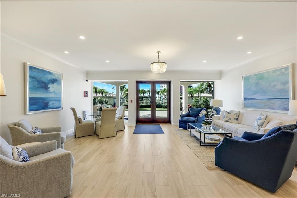 Living room featuring light wood-style floors, crown molding, french doors, and recessed lighting