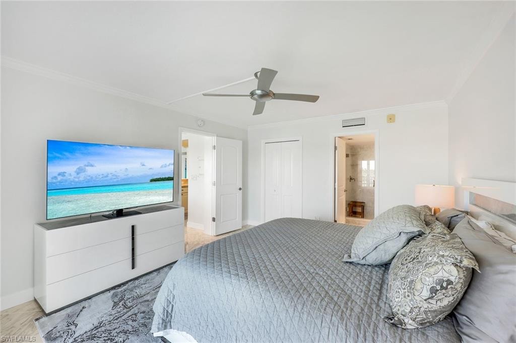 Bedroom featuring ensuite bath, crown molding, ceiling fan, and a closet