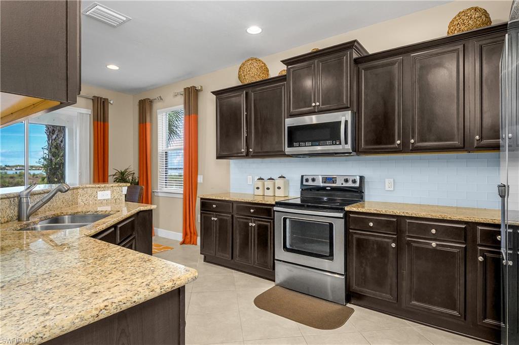 Open and spacious kitchen features granite countertops, stainless steel appliances, tile backsplash, pantry, and stunning views!