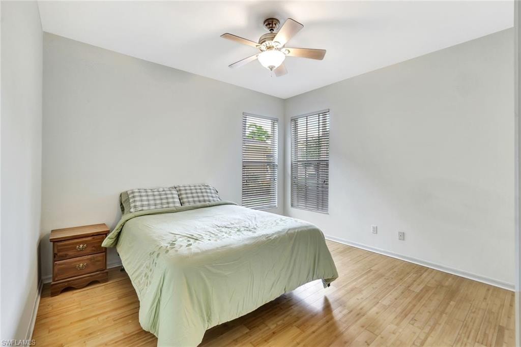 Bedroom with light wood finished floors, baseboards, and a ceiling fan