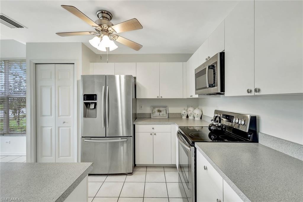 Kitchen featuring light tile patterned floors, ceiling fan, stainless steel appliances, light countertops, and white cabinetry