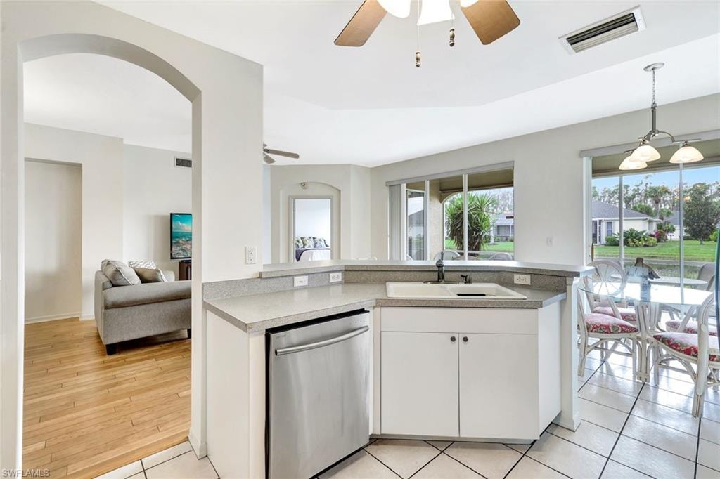 Kitchen featuring visible vents, stainless steel dishwasher, open floor plan, white cabinetry, and a sink