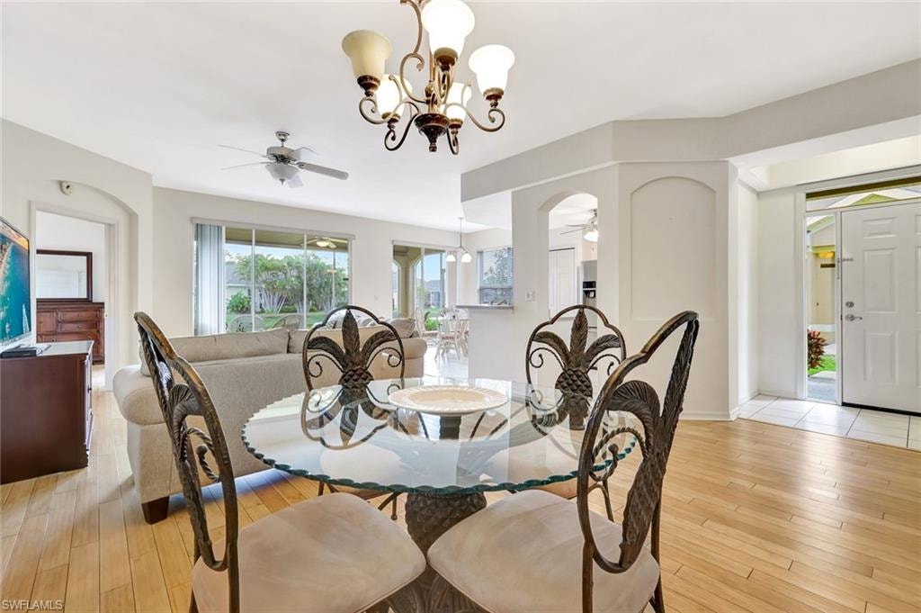 Dining space featuring light wood-style floors, baseboards, and ceiling fan with notable chandelier