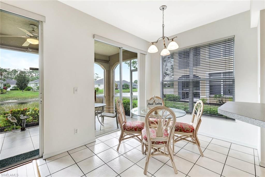 Dining area with ceiling fan with notable chandelier, plenty of natural light, and light tile patterned floors