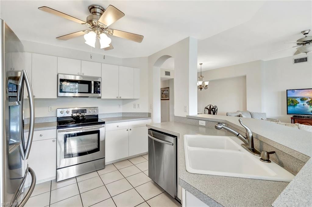 Kitchen with open floor plan, light countertops, appliances with stainless steel finishes, and a sink