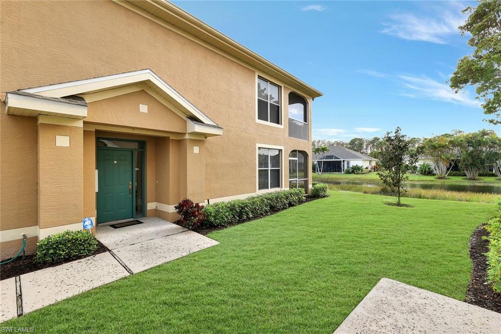 Entrance to property featuring a yard, a water view, and stucco siding