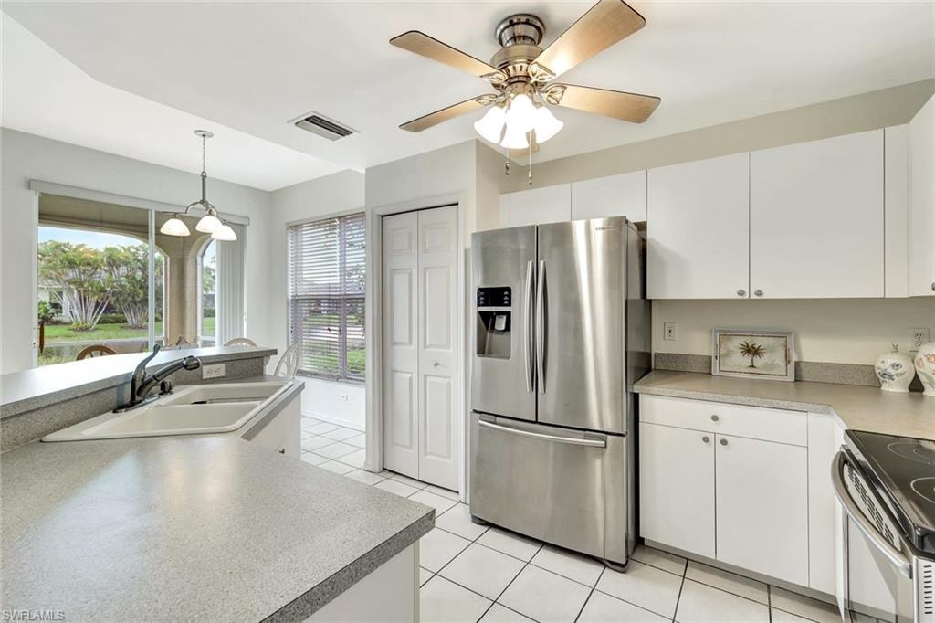 Kitchen with a sink, visible vents, white cabinets, appliances with stainless steel finishes, and pendant lighting