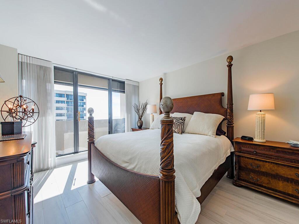 Bedroom with access to exterior, a wall of windows, and wood finished floors
