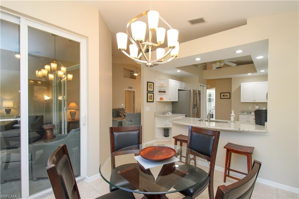 Dining area with light tile patterned floors, ceiling fan with notable chandelier, and sink