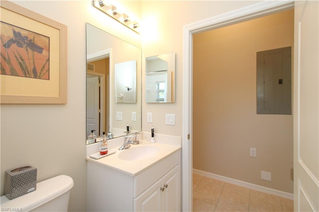 Bathroom featuring tile patterned flooring, vanity, toilet, and electric panel