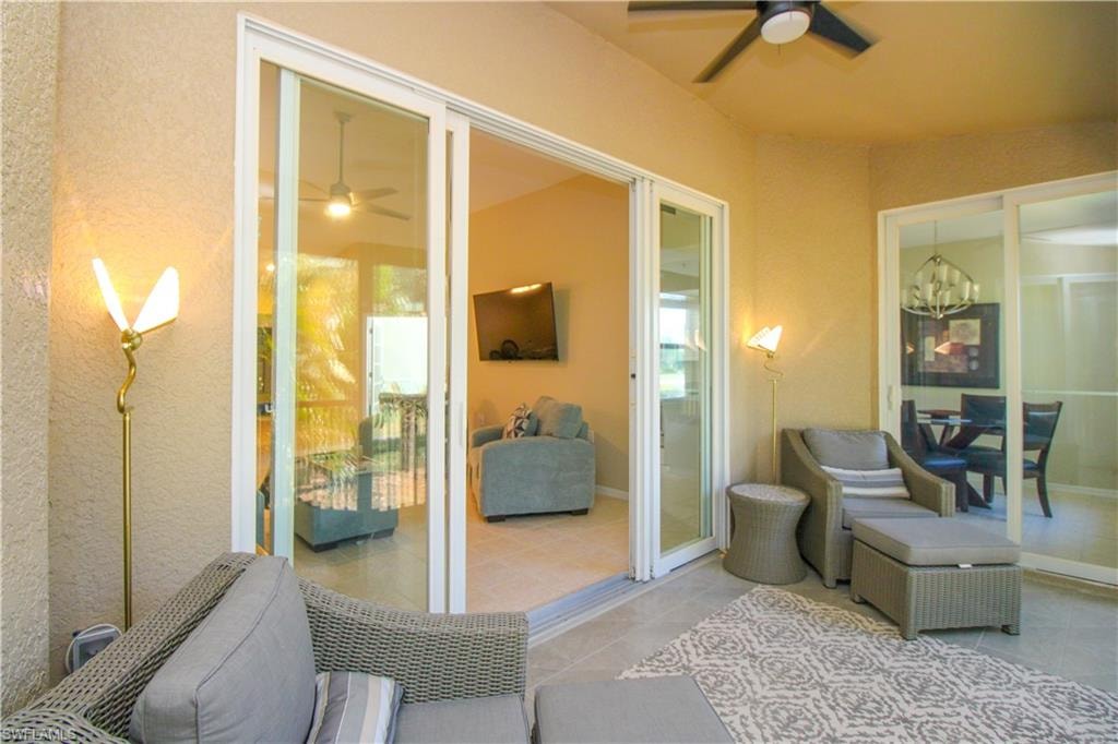 Sitting room with light tile patterned flooring and ceiling fan with notable chandelier