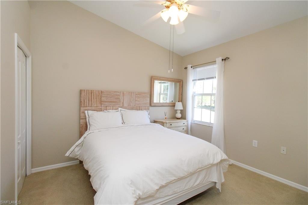 Carpeted bedroom featuring a closet, vaulted ceiling, and ceiling fan