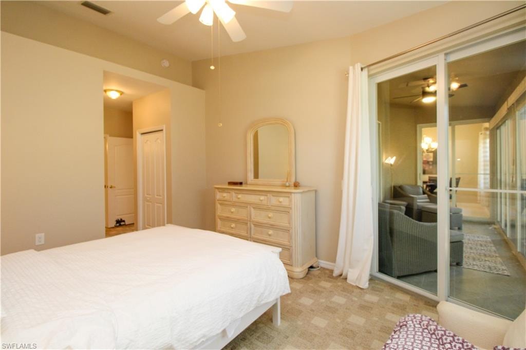 Bedroom with a closet, light colored carpet, and ceiling fan