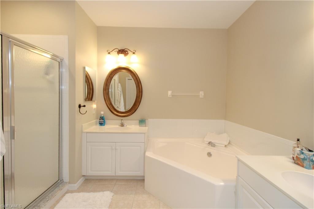 Bathroom featuring tile patterned floors, vanity, and separate shower and tub