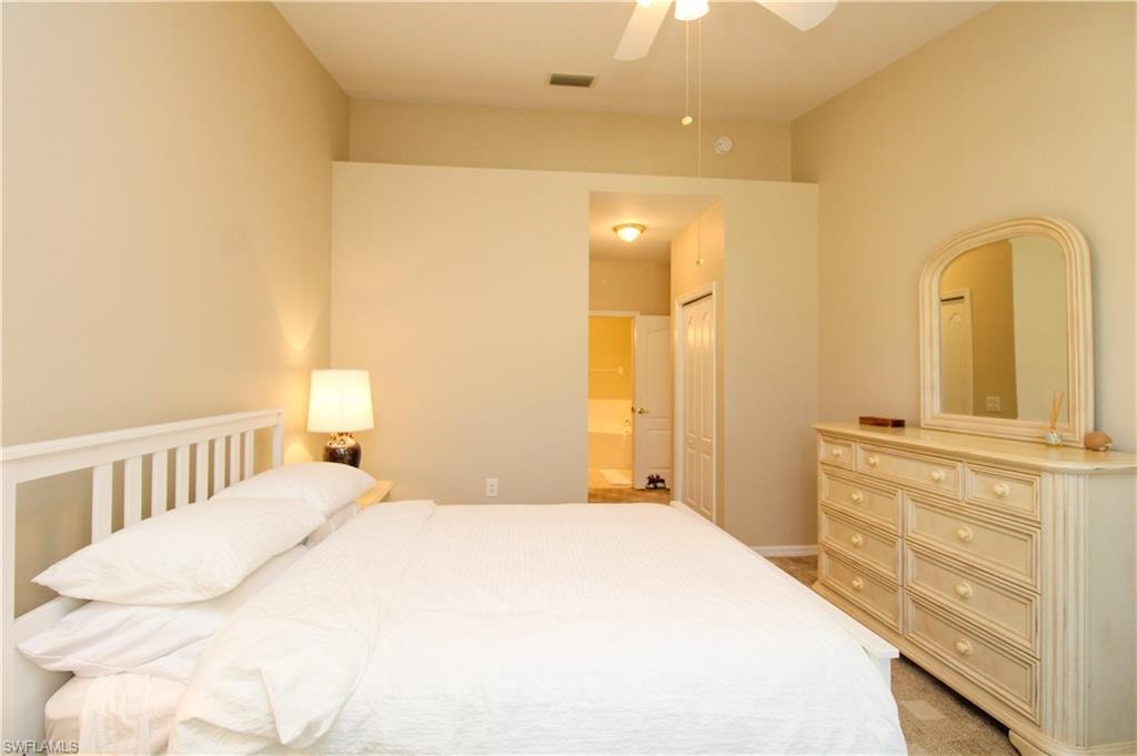 Carpeted bedroom with connected bathroom, ceiling fan, and a closet