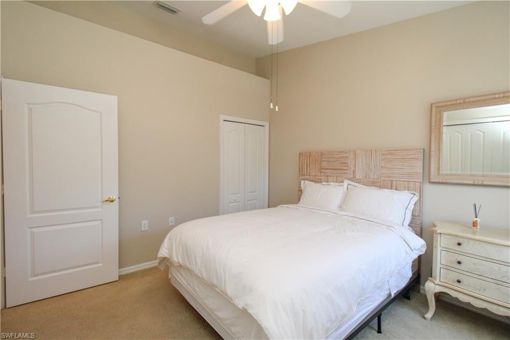 Carpeted bedroom featuring ceiling fan and a closet